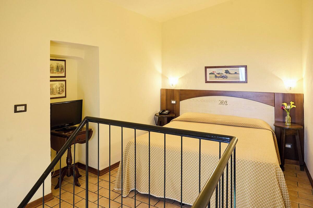 A hotel room with a bed, a TV, a telephone, and a picture on the wall.