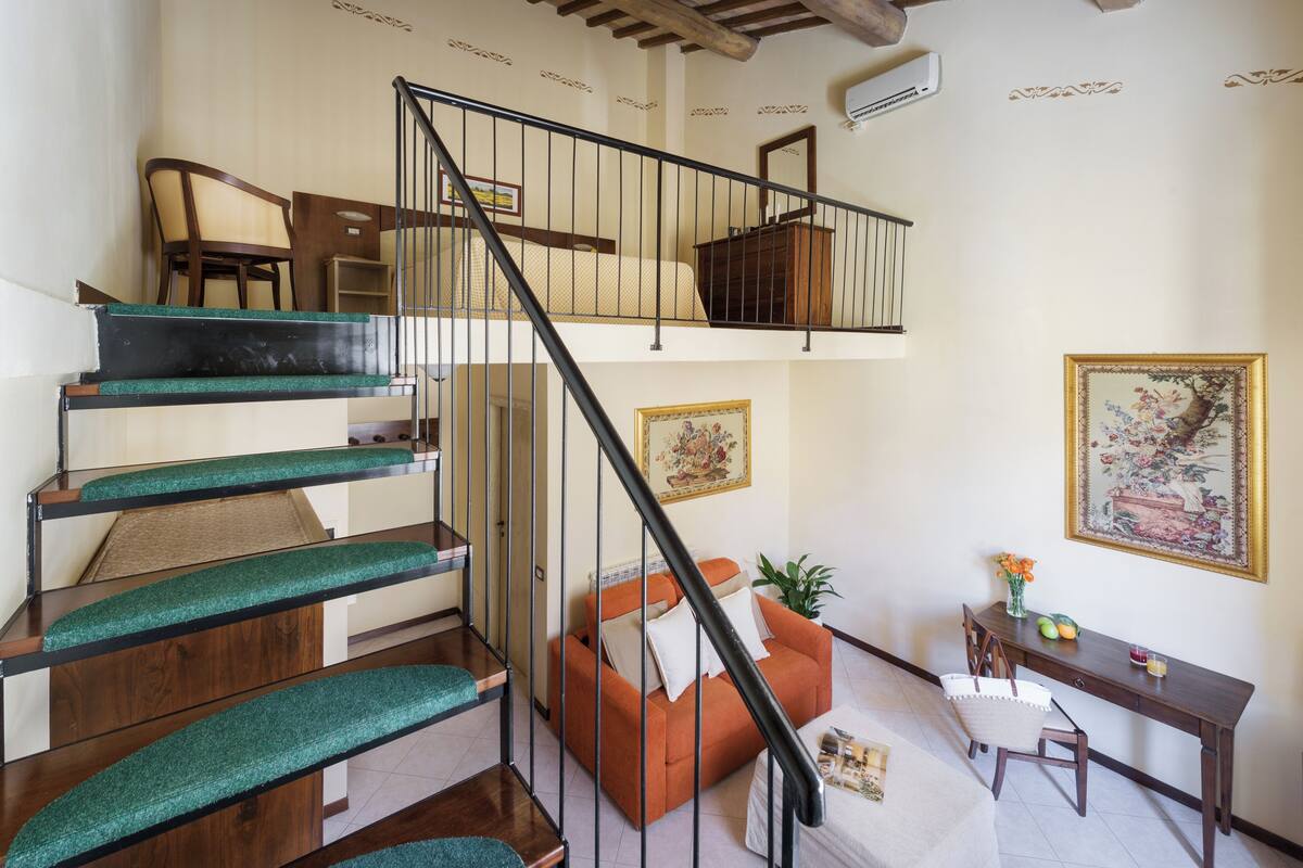 A staircase with green carpeted steps leading to a loft bedroom.