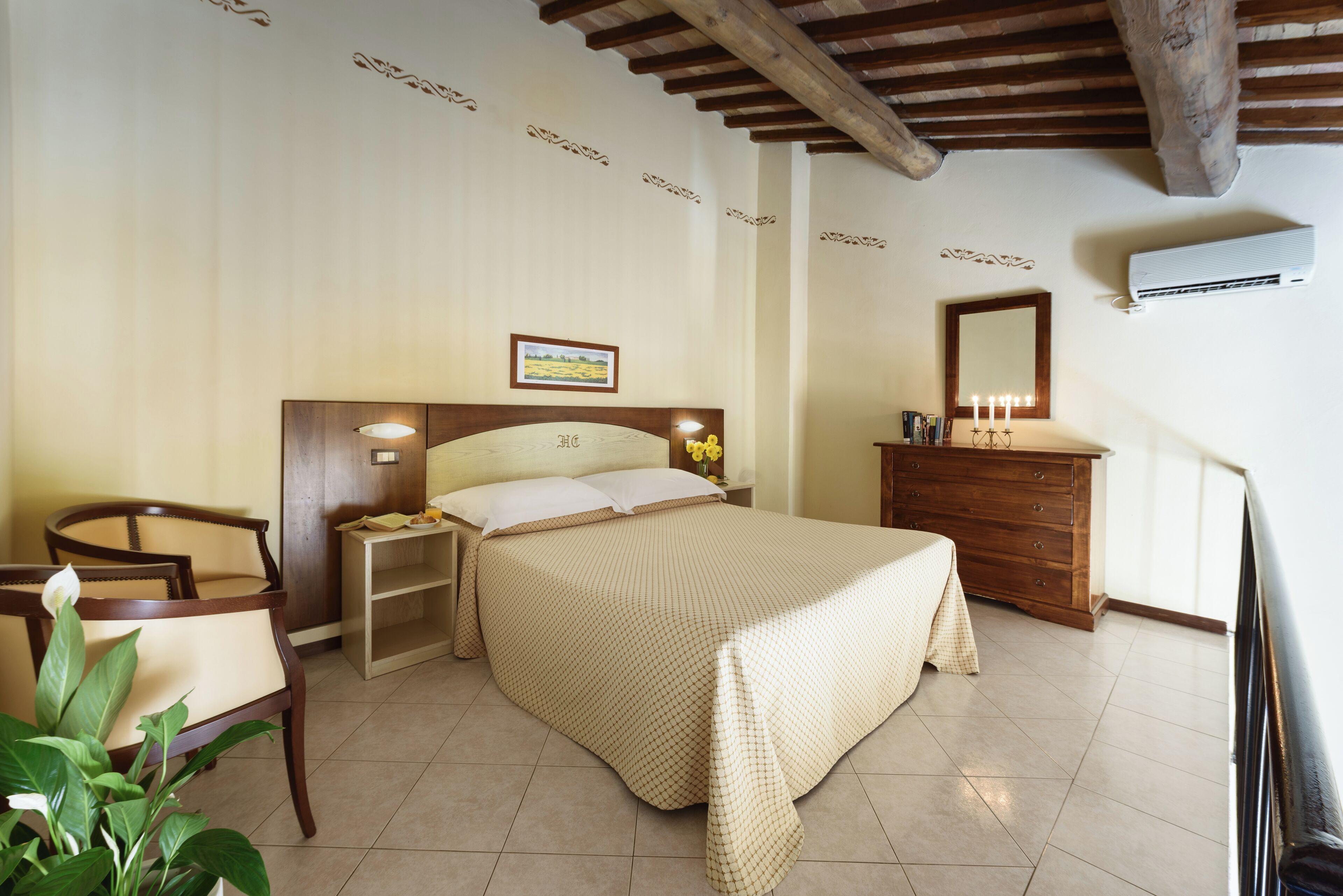 A bedroom with a bed, nightstand, dresser, chair, and a potted plant.