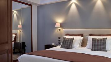 Una habitación de hotel con una cama grande, una mesita de noche con lámpara y un espejo.