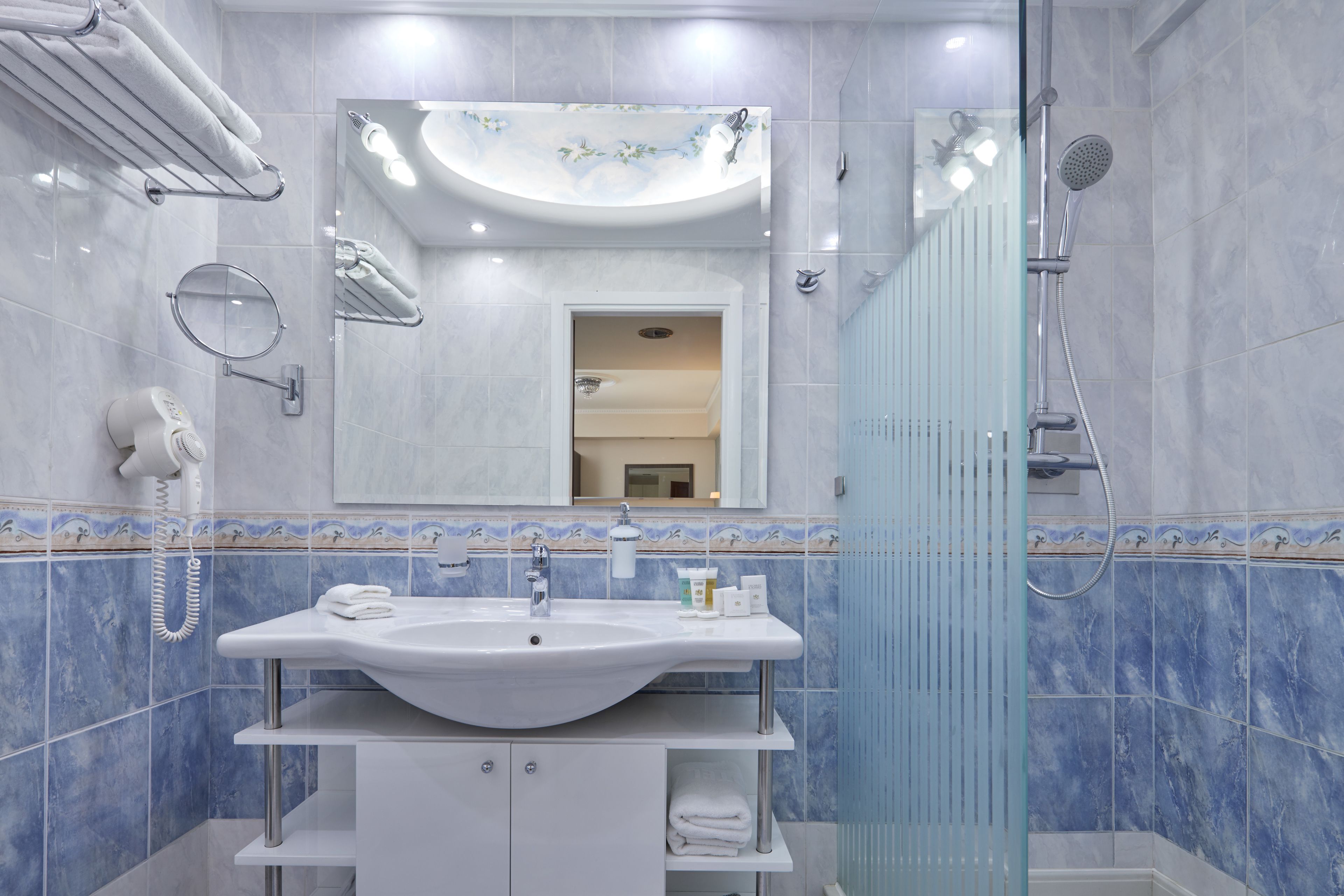 A bathroom with a white sink, mirror, and shower.