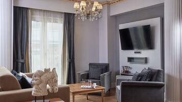 A modern living room with a chandelier, a flat-screen TV, and a horse sculpture on a coffee table.