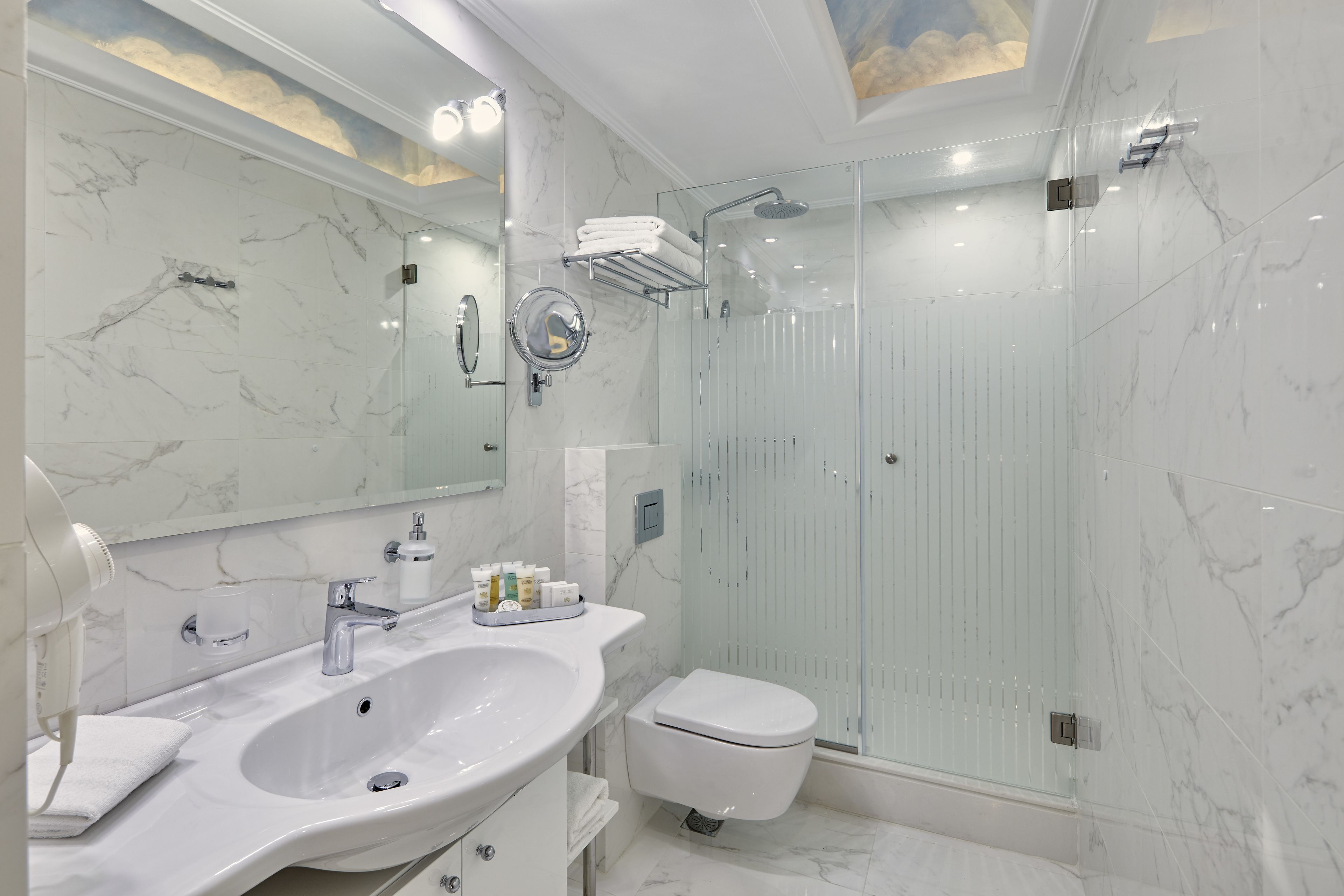 Un bagno moderno con lavandino in marmo, servizi igienici e cabina doccia in vetro.