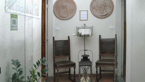 A room with two antique chairs, a small table with a lantern, and a wall-mounted plaque. - B&B Dante e Beatrice (Florence)