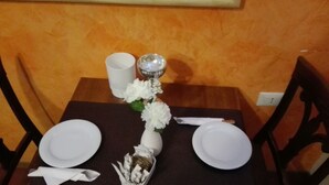 A dining table set with white plates, a white napkin, a vase with white flowers, and a decorative glass object. - B&B Dante e Beatrice (Florence)