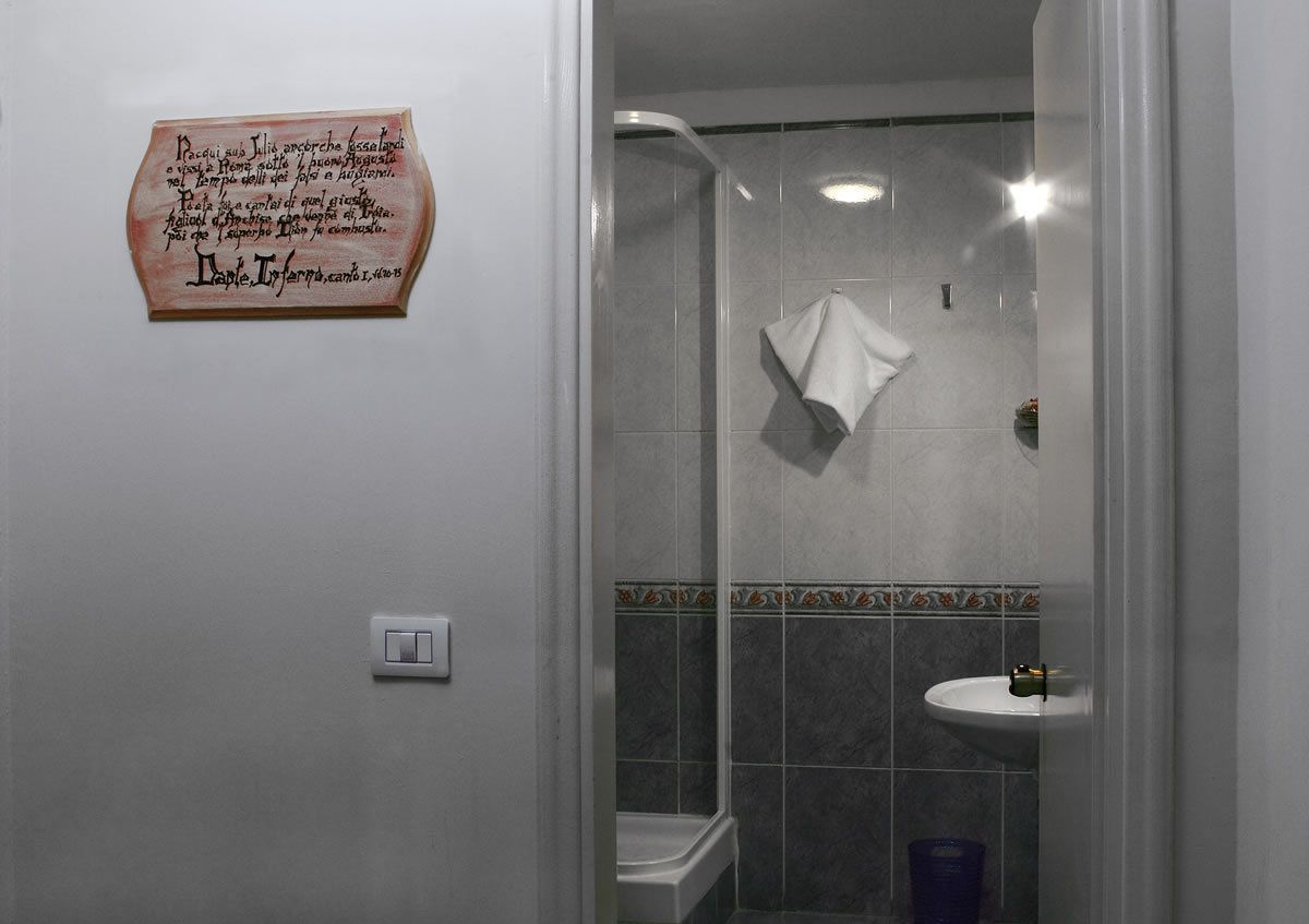 A bathroom with a shower, a sink, and a towel hanging on the wall.