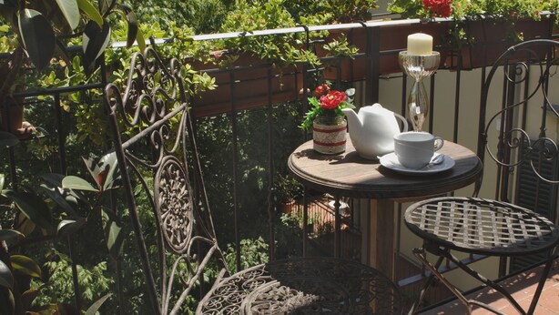A small outdoor seating area with two metal tables and chairs, a white teapot, a white cup, and a candle on a small table. - B&B Dante e Beatrice (Florence)