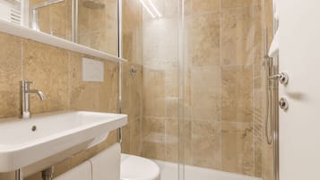Une salle de bain moderne avec une douche à parois de verre, un lavabo blanc et des toilettes.