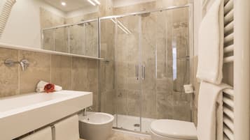Un baño moderno con ducha de vidrio, lavamanos blanco y retrete.