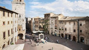 A historic square with stone buildings, a central fountain, and a tower. - La Cisterna (San Gimignano)