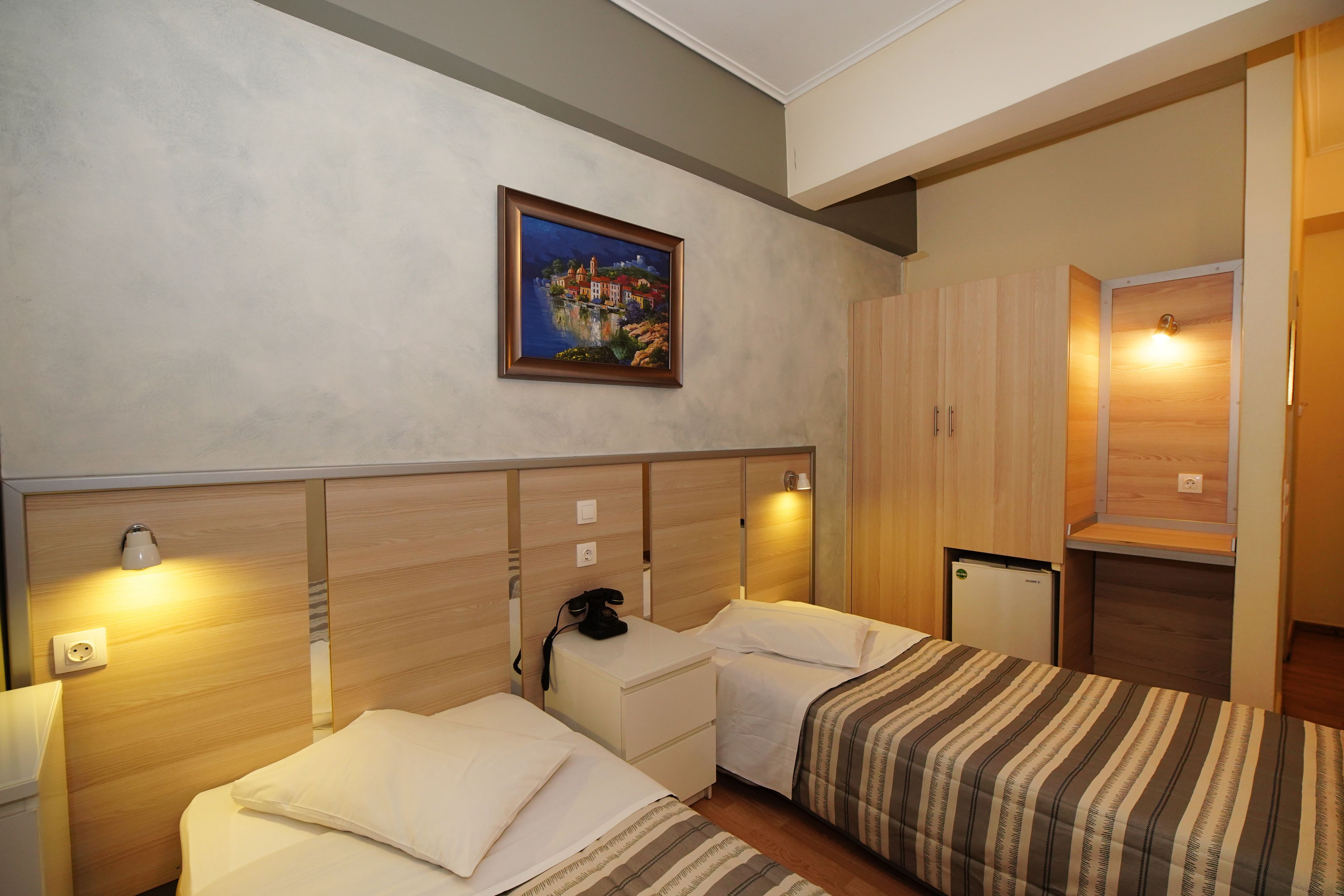 Une chambre d’hôtel avec deux lits, un tableau au mur et une petite kitchenette.