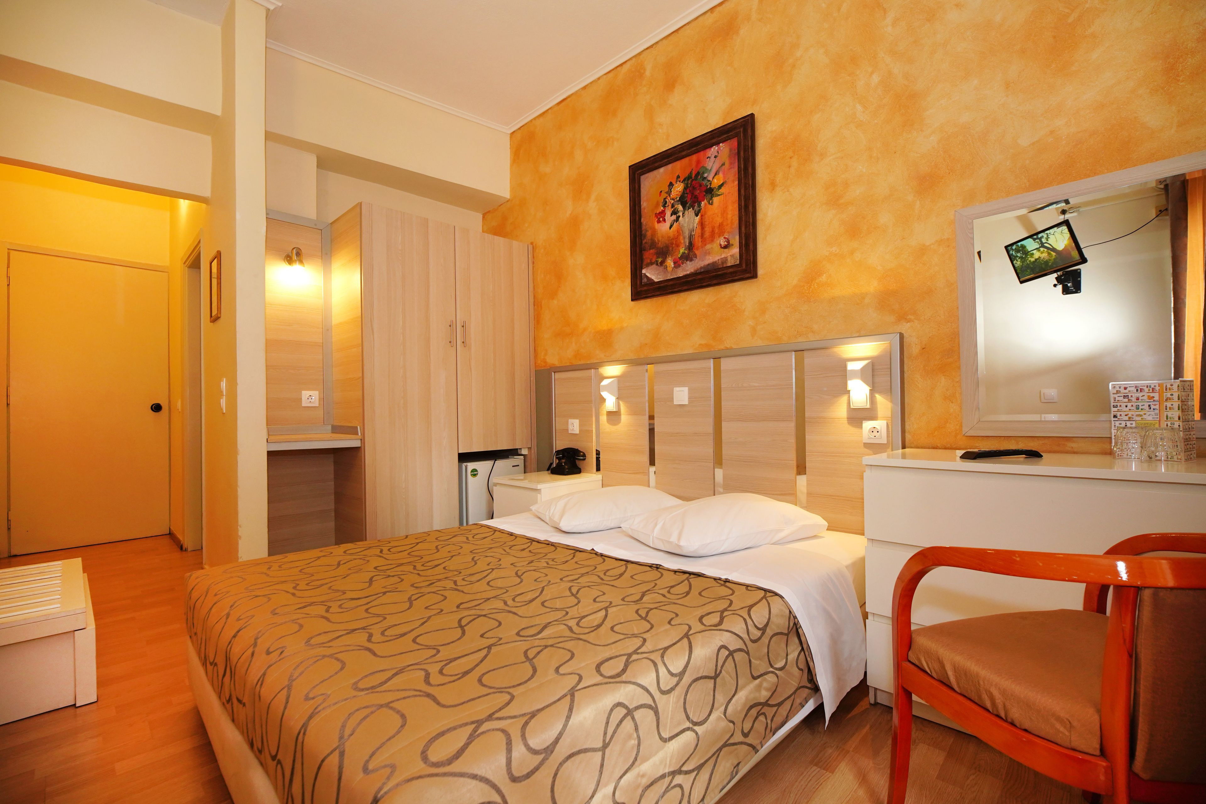 Ein Hotelzimmer mit Bett, Schreibtisch, Stuhl, Spiegel und einem Bild an der Wand.