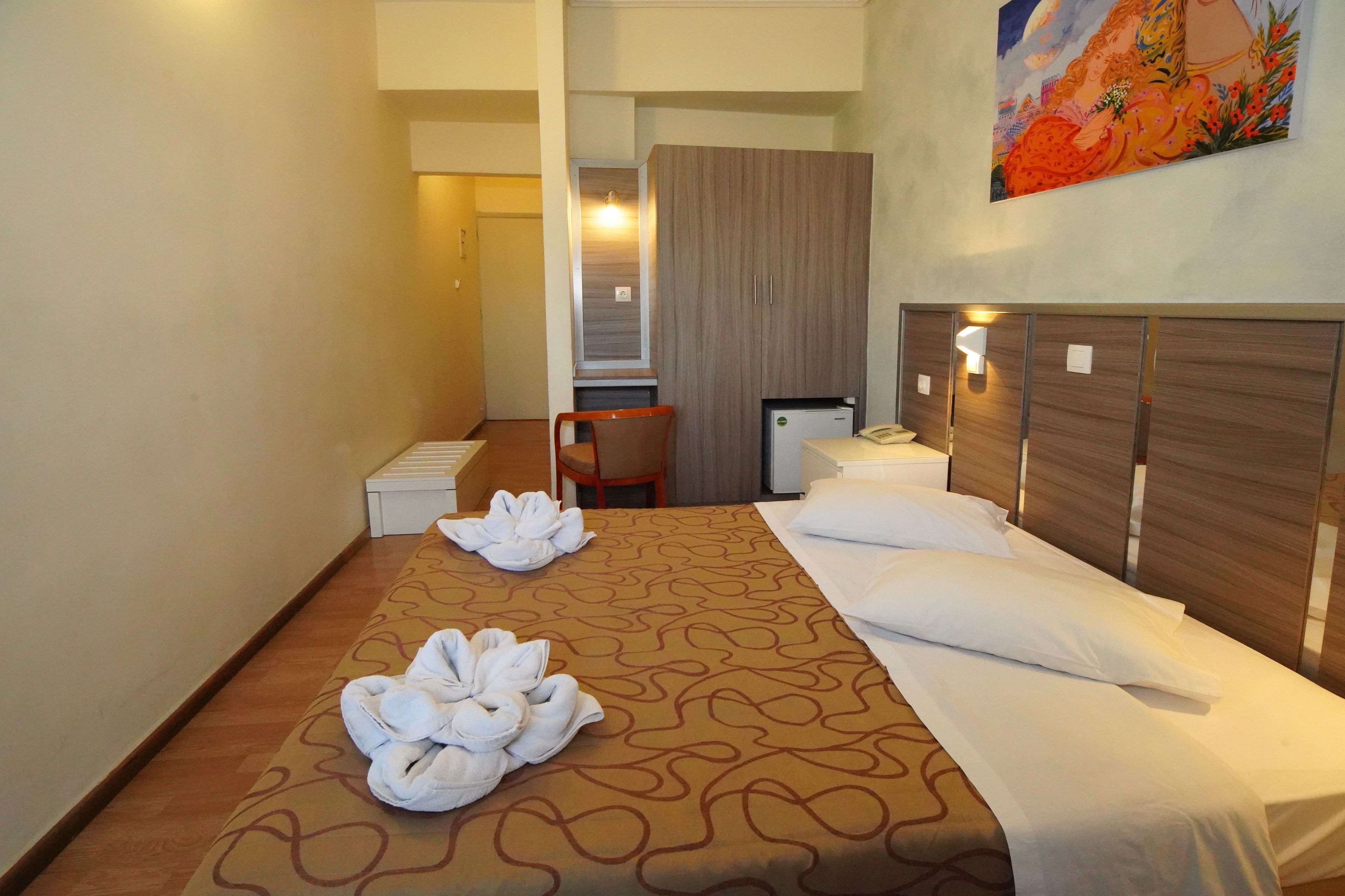 Habitación de hotel con cama, escritorio, silla y un cuadro en la pared.