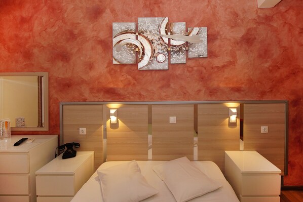 A modern bedroom with a wooden headboard, bedside tables, and a large mirror.