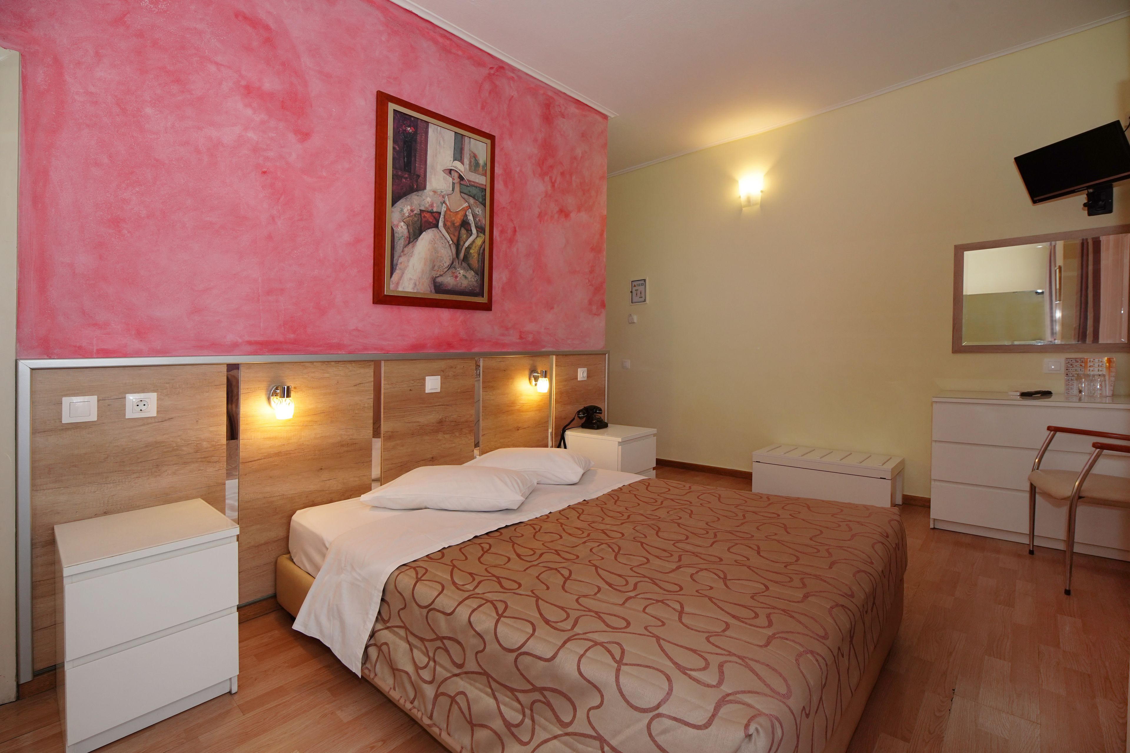 A bedroom with a large bed, bedside tables, a dresser, a mirror, and a painting on the wall.