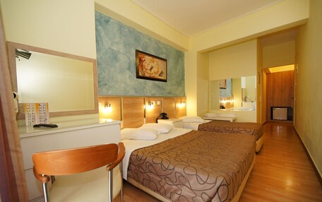 A hotel room with a bed, a desk, a chair, a mirror, and a painting on the wall.