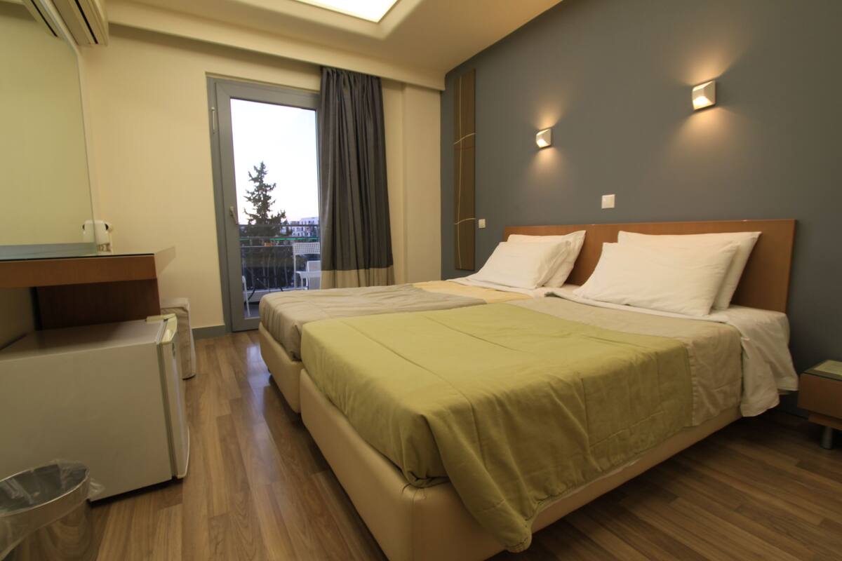 Ein Hotelzimmer mit einem Bett, einem kleinen Schreibtisch, einem Papierkorb und Blick nach draußen.