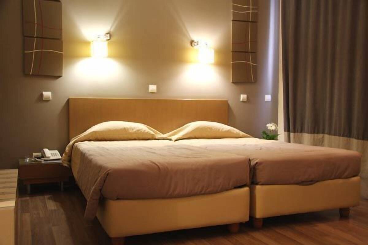 Ein Doppelbett mit Holz Kopfteil, zwei Nachttische und ein Beistelltischchen mit Telefon.