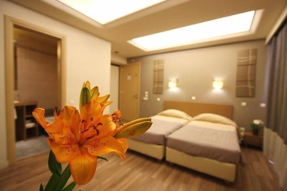 Ein Hotelzimmer mit einem Bett, Nachttischen und einer Blume im Vordergrund.