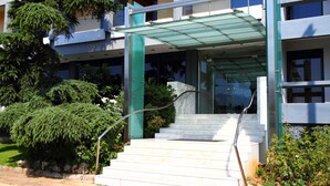 A building with a glass entrance, white steps, and a green awning. - Pines Hotel (Kifisia)