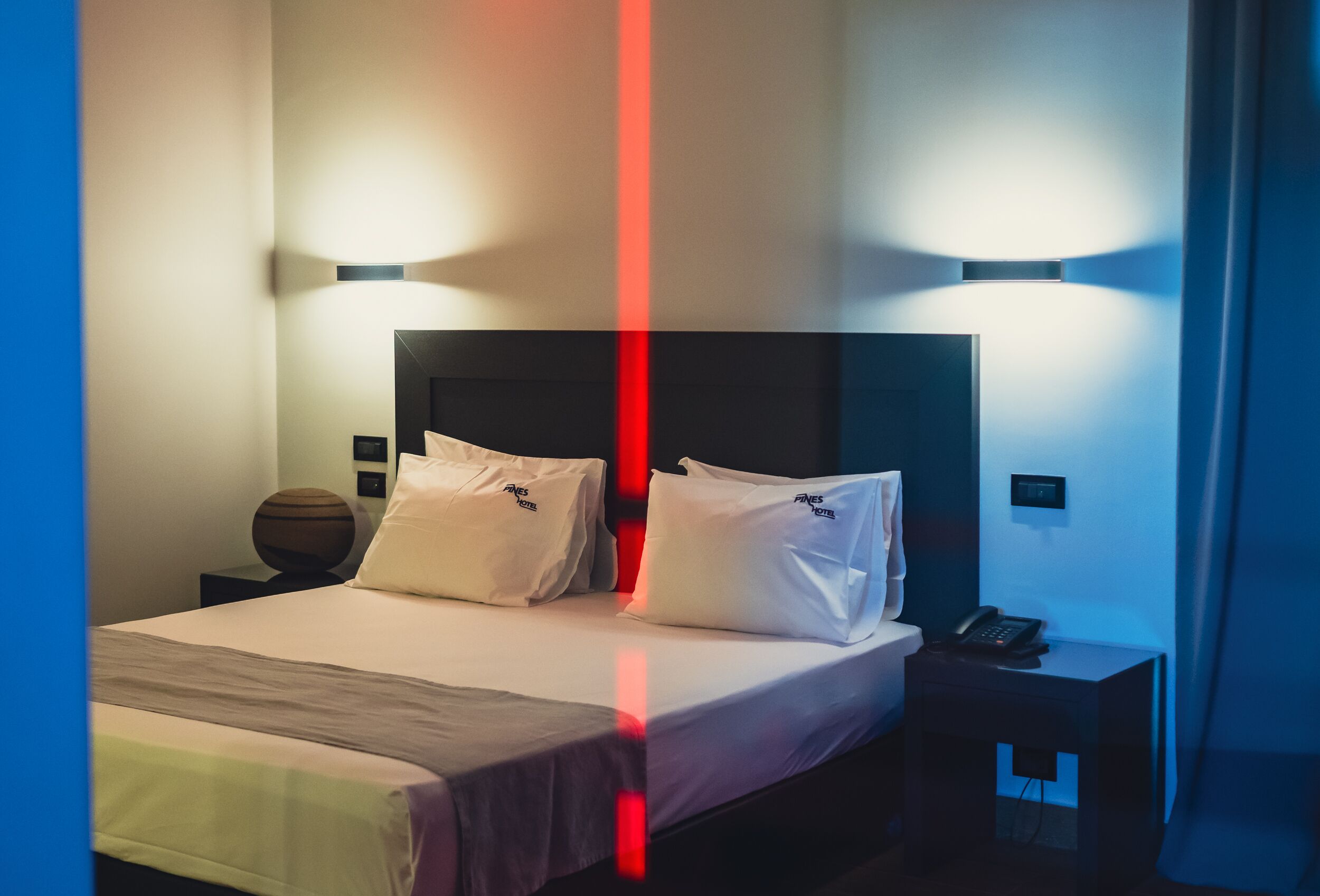A hotel room with a large bed, two bedside tables, and a nightstand with a phone.