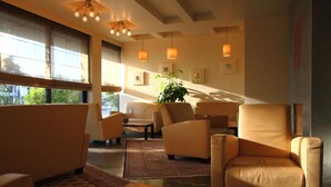 A modern lounge area with leather sofas and armchairs, a coffee table, and pendant lighting. - Pines Hotel (Kifisia)