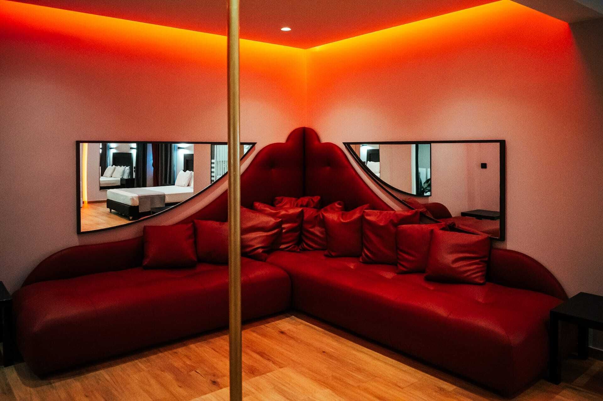 A modern room with a red sectional sofa, two large mirrors, and a wooden floor.