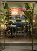 A restaurant with a glass enclosure, featuring a booth seating area and a view of the street with neon signs.