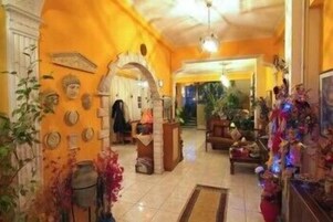 Un interior cálidamente iluminado con suelo de baldosas, una zona de estar central y una puerta que da a otra habitación.