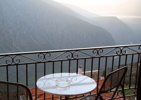 Un balcón con una mesa redonda y dos sillas, con vista a un paisaje montañoso.