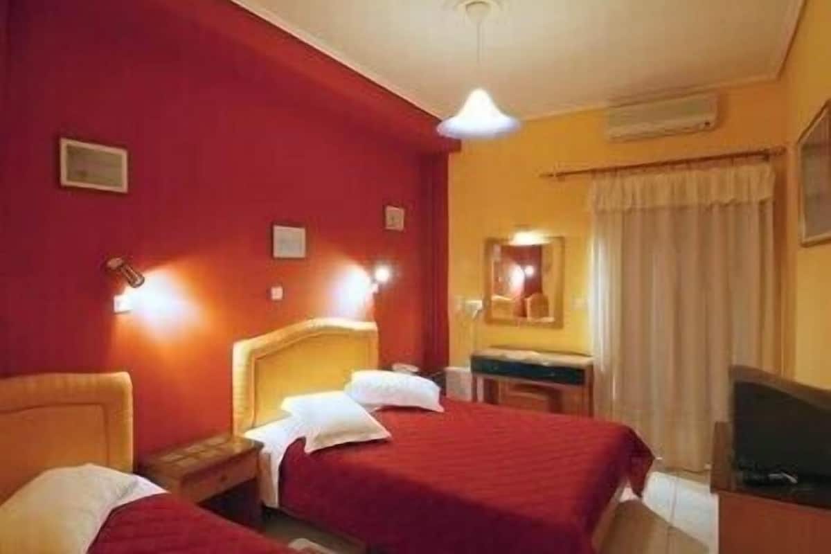 A hotel room with two beds, a desk, a mirror, and a television.