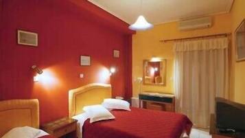 A hotel room with two beds, a desk, a mirror, and a television.