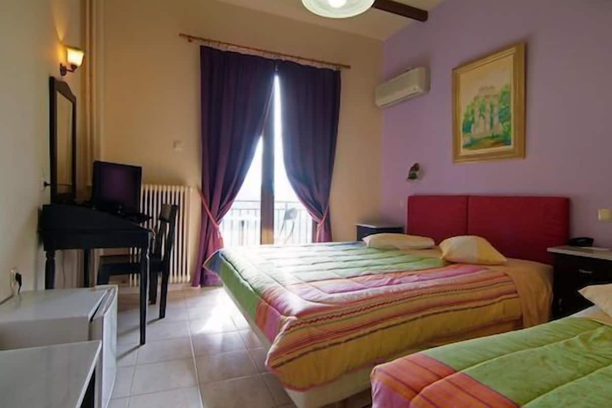 A hotel room with two beds, a desk, a chair, a radiator, and a window with curtains.