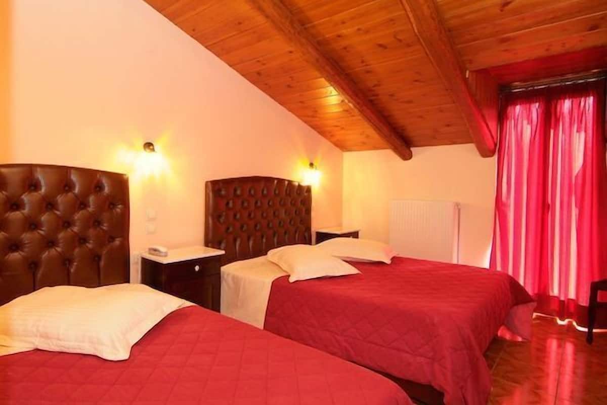 A hotel room with two beds, wooden headboards, and a red curtain.