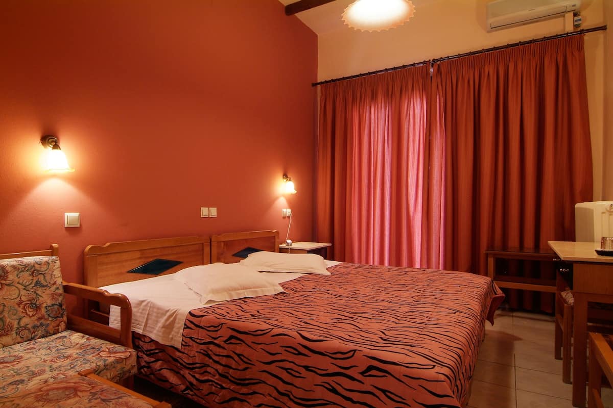 A hotel room with a bed, a chair, a desk, and a curtain.