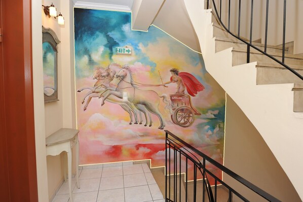 A staircase with a mural of horses and a figure on a chariot.