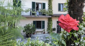 A building with a balcony, potted plants, and a red rose. - Crotto Regina (Gravedona)