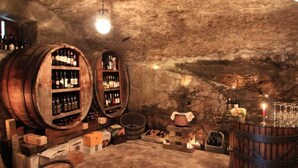 A cellar with wooden barrels and shelves of wine bottles. - Crotto Regina (Gravedona)