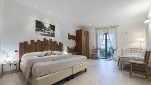 A bedroom with a large bed, a wooden headboard, a nightstand, a chair, and a window with curtains. - Crotto Regina (Gravedona)