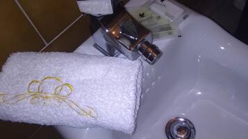 Un lavabo de salle de bain avec une serviette, une boîte de mouchoirs et des articles de toilette.