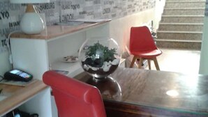 A dining area with a wooden table, red chairs, a glass-top table, a white lamp, and a decorative bowl with plants.