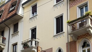 A hotel with a sign reading 'HOTEL' and 'MALTA' on the facade, multiple windows with shutters, and balconies with plants.