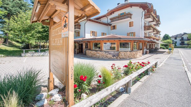 A hotel with a wooden facade, multiple balconies, and a covered outdoor seating area.