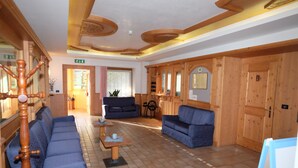 A spacious lobby with a blue sofa, wooden cabinets, and a tiled floor.
