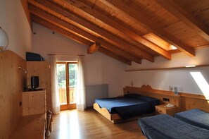 Un dormitorio tipo cabaña de madera con techo alto, una cama, un escritorio y una ventana.