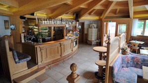 A wooden interior with a bar area, seating, and a staircase.