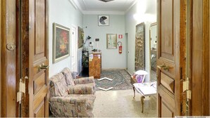 Un couloir avec des portes en bois, un canapé à motifs, une petite table et un projecteur au plafond.