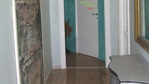 Un couloir avec une porte portant l’inscription « Alberto Sandro Roma » et un tableau accroché au mur gauche.
