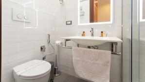 A modern bathroom with a toilet, bidet, and a glass shower enclosure. - Hotel Fiorella Milano (Milan)