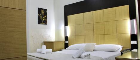 A hotel room with a large bed, a wooden headboard, a bedside table, and a wall-mounted picture.